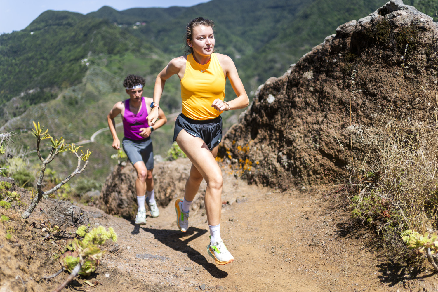 People running on a mountainous trail in Tenerife.