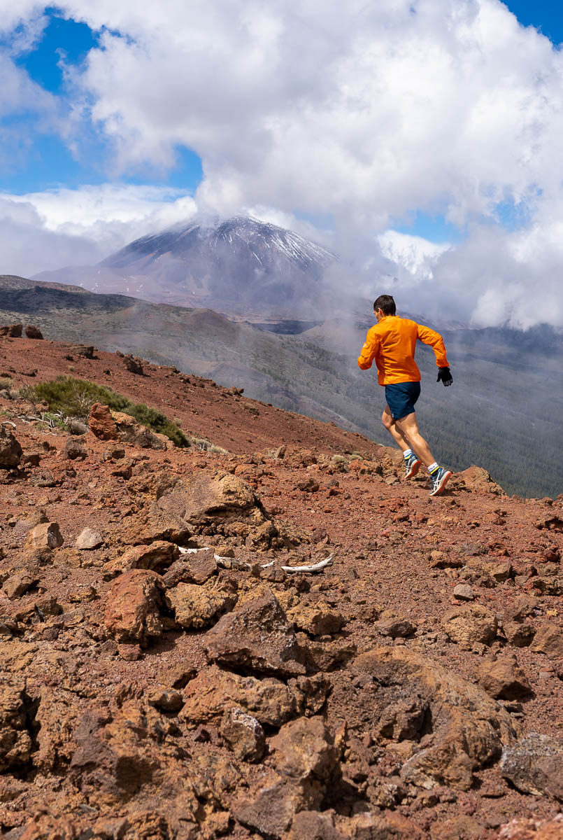 Runner on the Teide trail, Tenerife, with cloudy skies and mountains in the background.