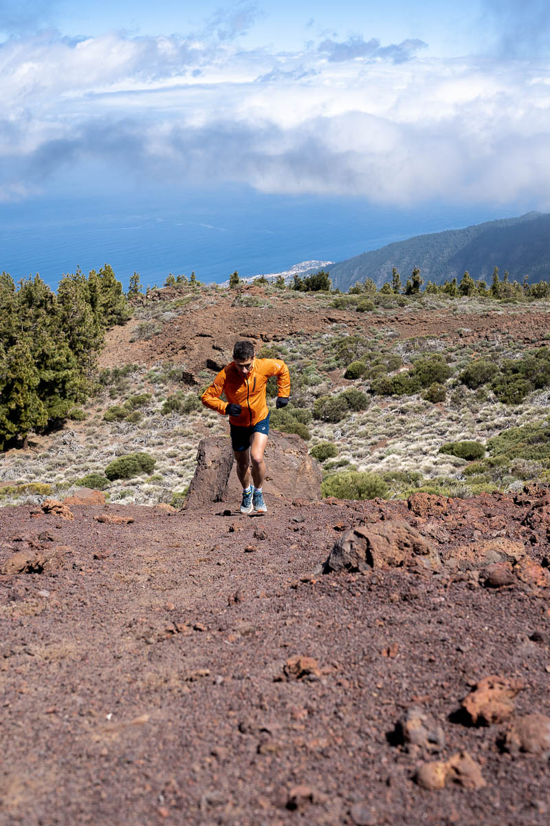 Person running on a mountainous trail in Tenerife with sea views.