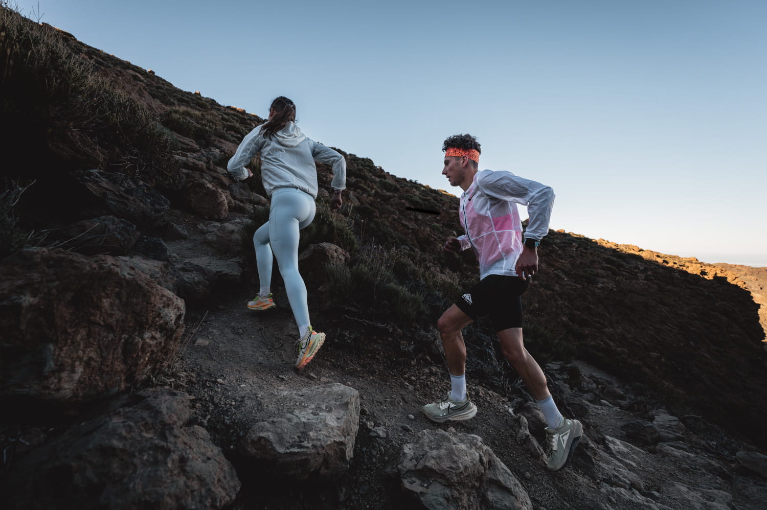 People running along a rocky path in Tenerife at dawn.