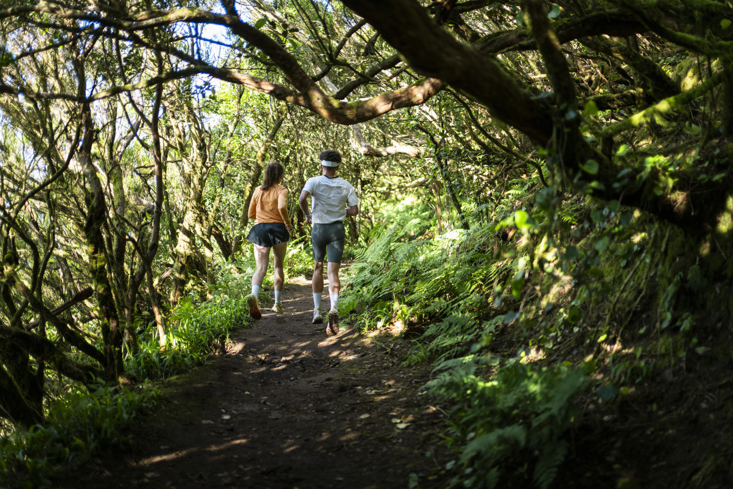 Two people run along a path surrounded by vegetation in Tenerife.