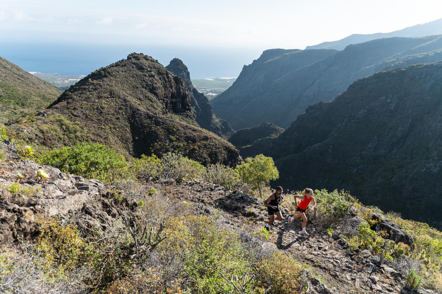 Trail in the mountains of Tenerife with two people running.