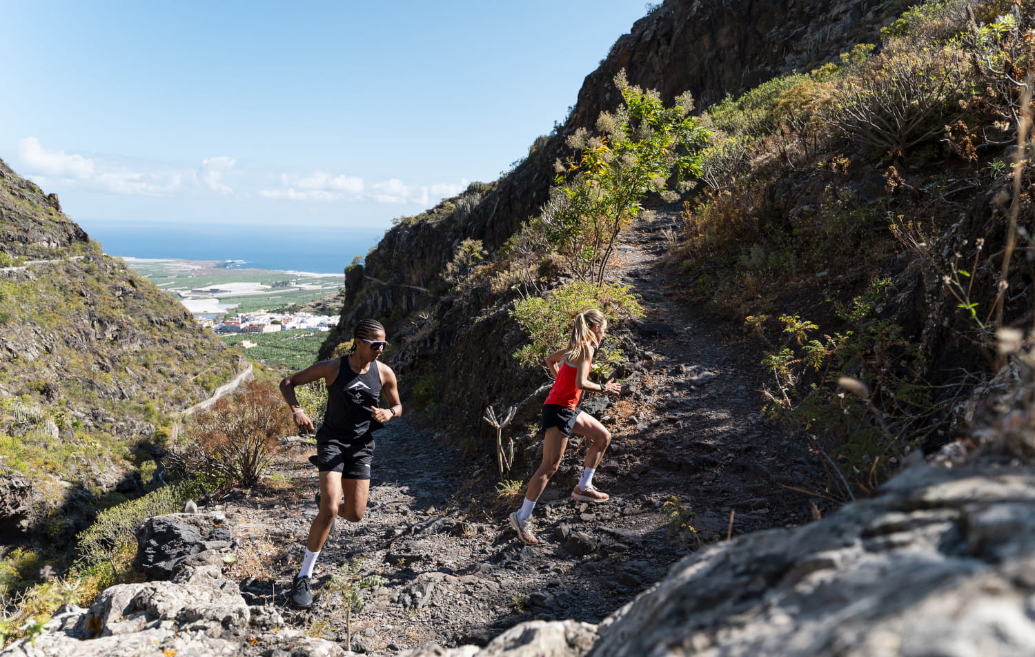 Runners on a rocky slope overlooking the sea in Tenerife.