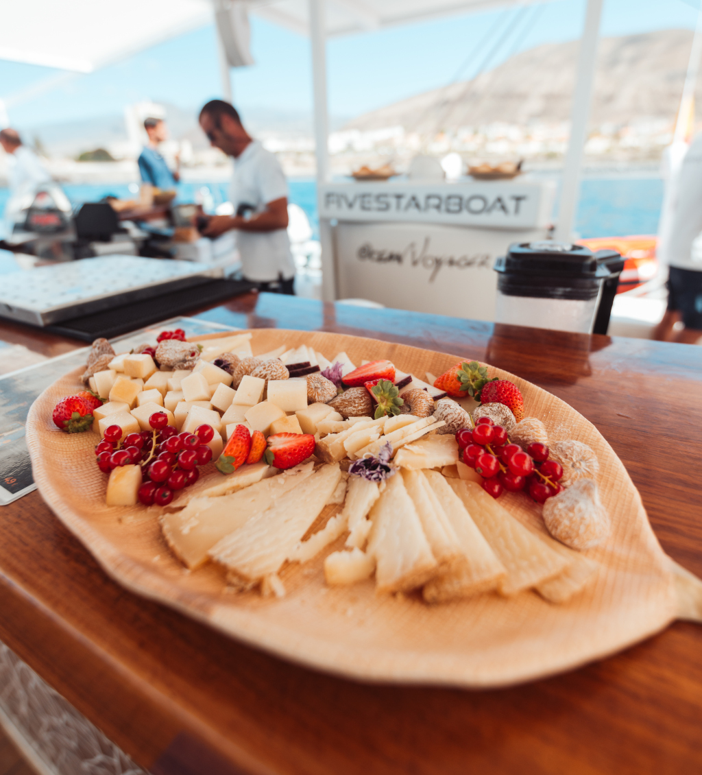 Cheese and fruit tray by boat in Tenerife, seabed and mountains.