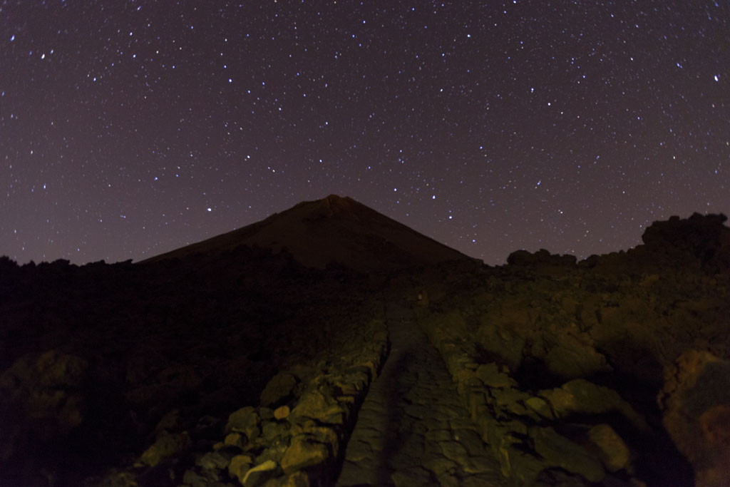 Starry sky over Mount Teide in Tenerife, with rocky path in the foreground.