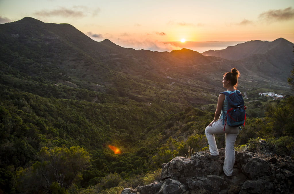 Person with backpack watches the sunset from a viewpoint in the mountains of Tenerife.