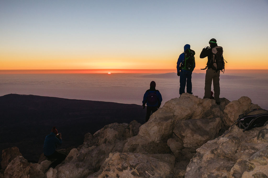 Mountaineers watching the sunrise from the summit of Mount Teide in Tenerife.