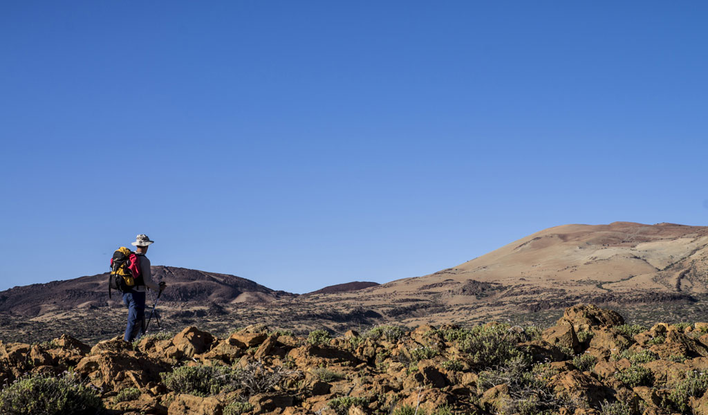 Person with backpack contemplating the mountainous landscape of Tenerife.