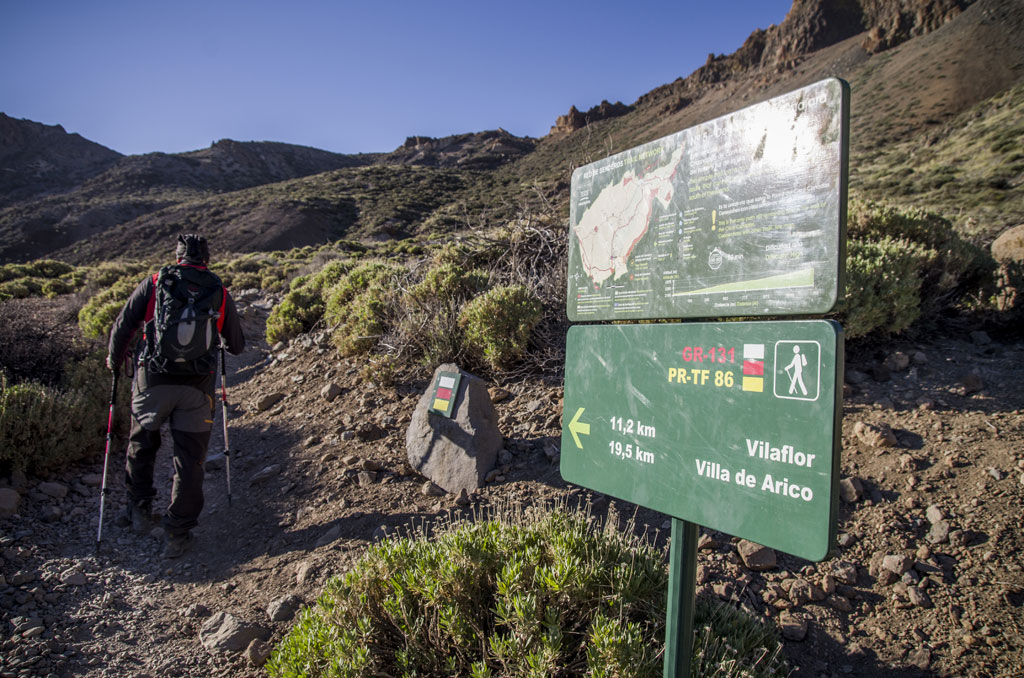 Hiker on his way to Vilaflor, Tenerife, next to signs of routes and distances.