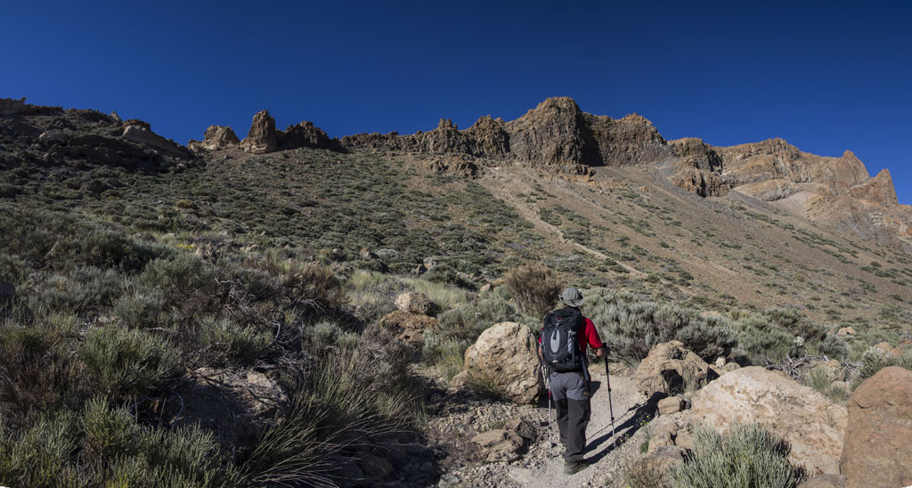 Person walking on rocky trail into mountains in Teide National Park, Tenerife.
