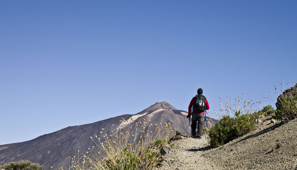 Person walking towards Mount Teide on a mountain trail in Tenerife.