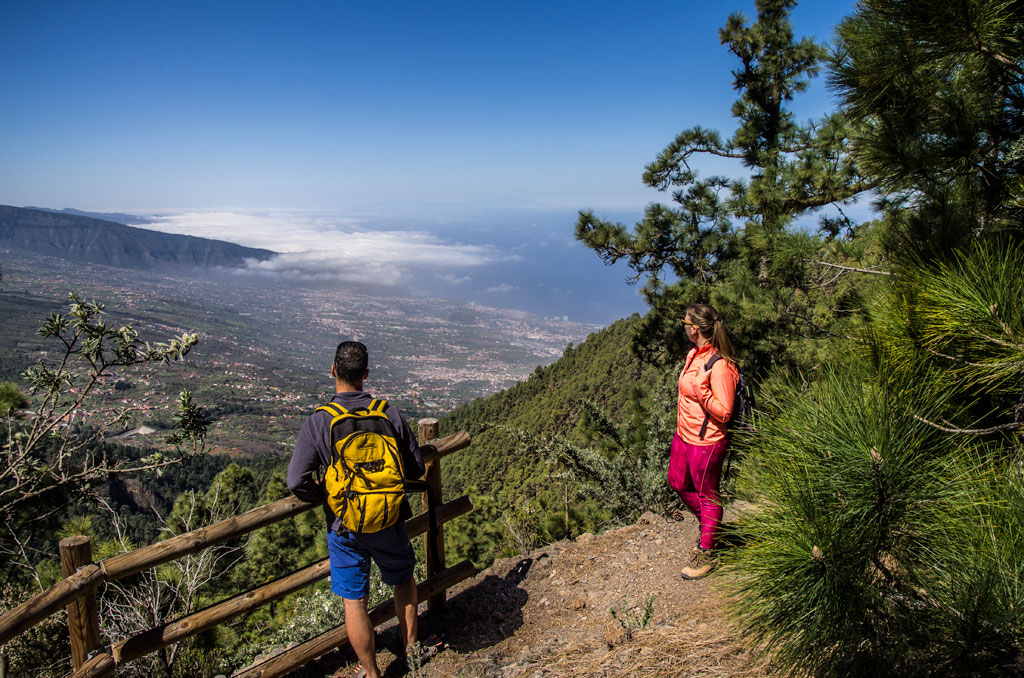 Two people with backpacks observe the landscape from a viewpoint in Tenerife.