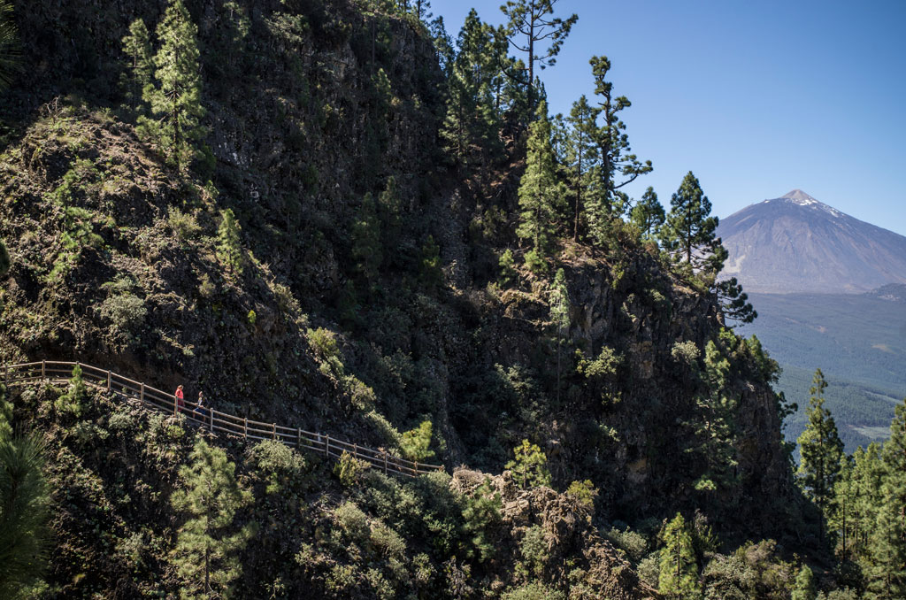 Mountainous trail with a view of Mount Teide in Tenerife and people walking.