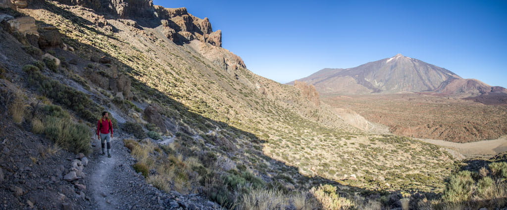 Hiker walking on a trail with Mount Teide in the background in Tenerife.