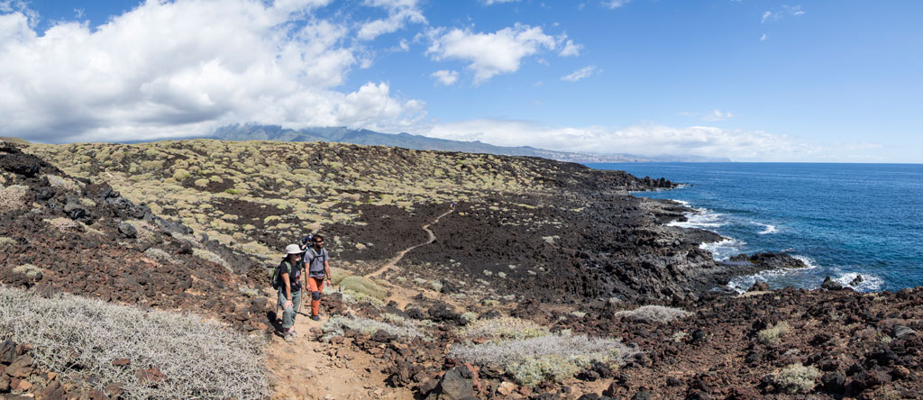 People walking along rocky path near the coast in Malpais de Güímar, Tenerife.