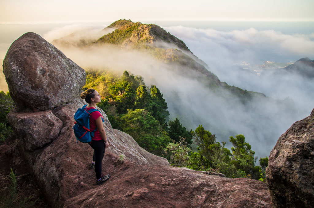 Person with backpack observes mountains and clouds in Tenerife.