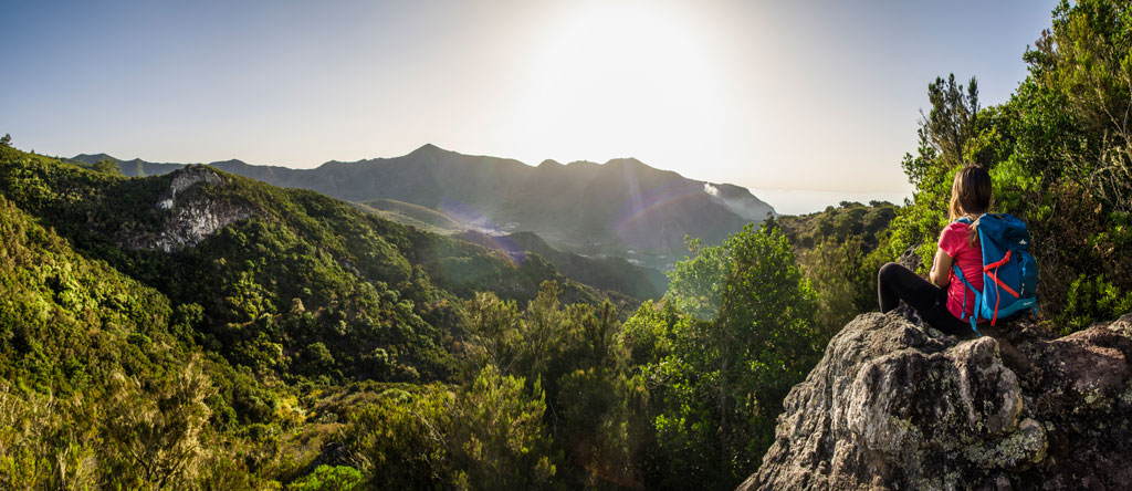Person with backpack looking at the mountainous landscape in Tenerife at sunset.