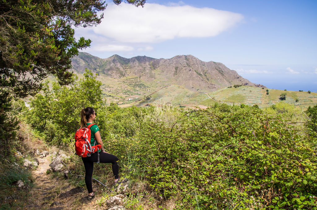 Person with red backpack walking on a mountain trail in Tenerife.