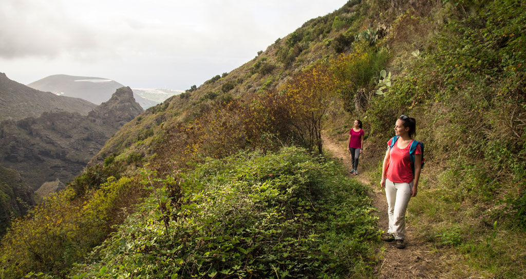 Two people walking along a trail in the mountainous landscape of Tenerife.
