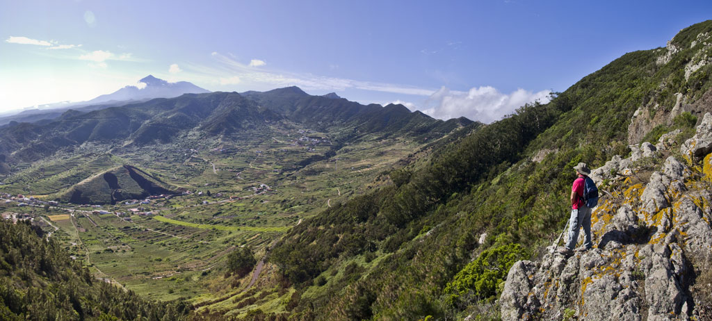 Hiker contemplates the mountainous landscape of Tenerife with Mount Teide in the background.