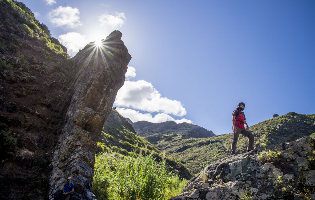 Person hiking in the Masca ravine, Tenerife, with the sun shining behind him.