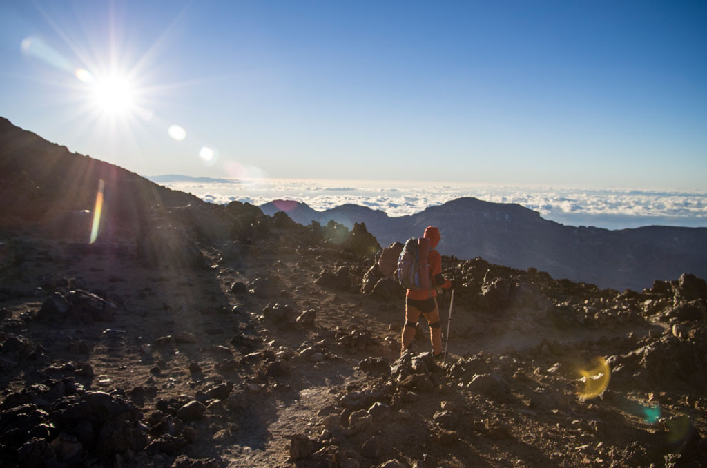 Hiking on rocks in the Teide National Park in Tenerife under a clear sky.