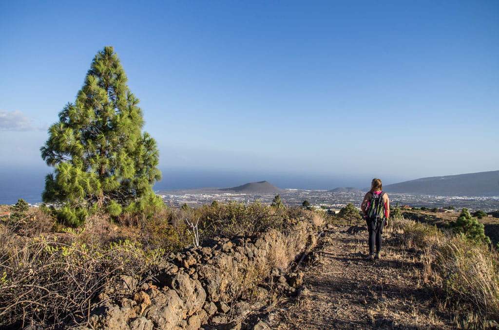 Person walking on a trail in Las Cañadas del Teide, Tenerife, overlooking the sea.