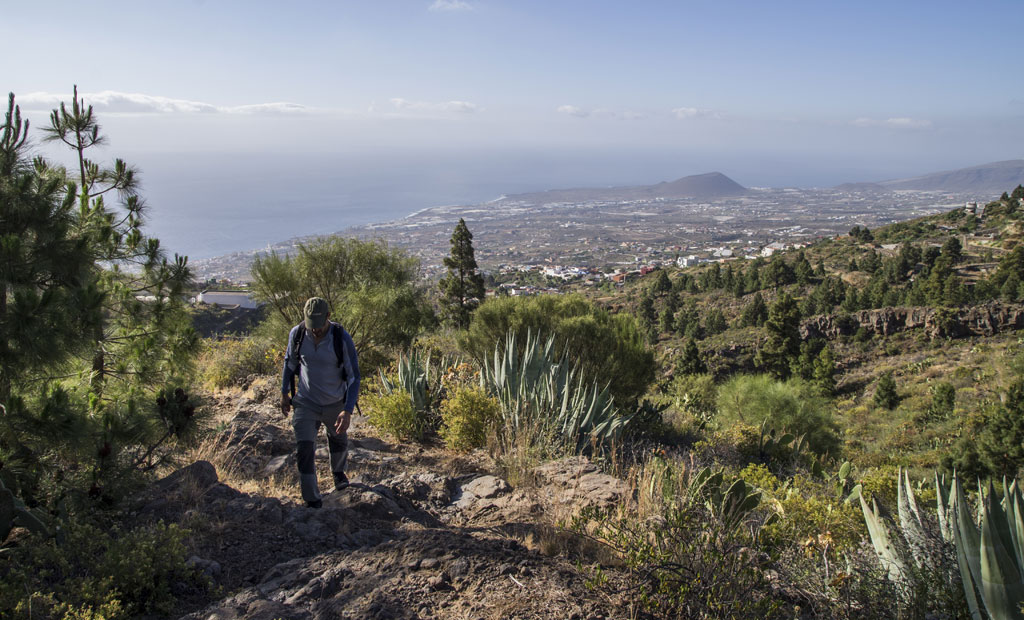 Hiker in the mountainous landscape of Tenerife with a view of the sea.