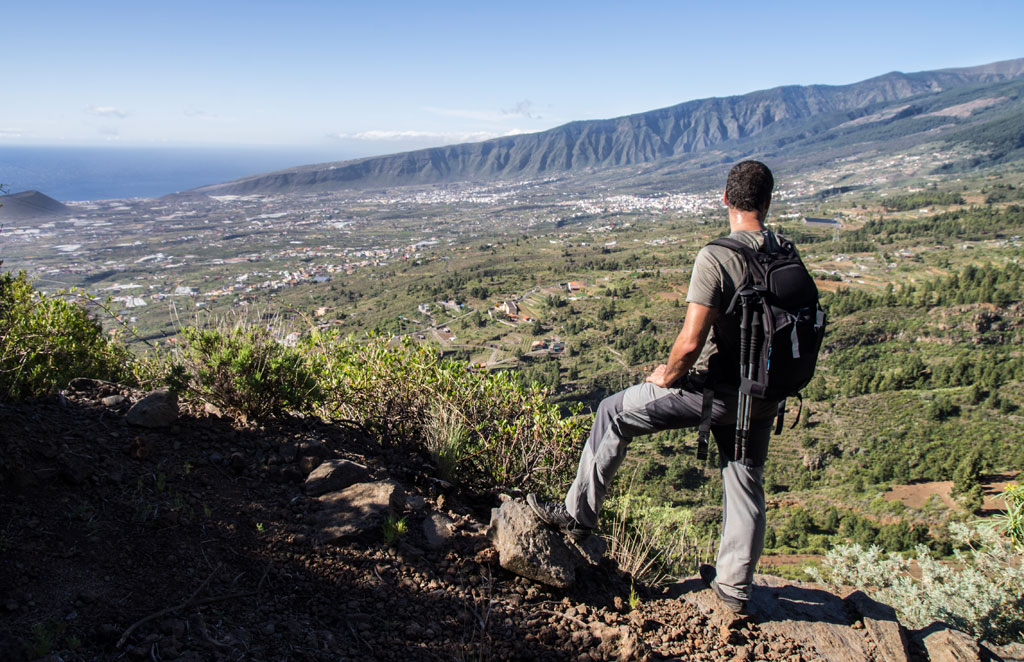 Person with a backpack observing the mountainous landscape of Tenerife from a viewpoint.