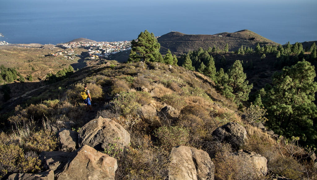 Mountainous trail in Tenerife with sea views and a hiker with a backpack.