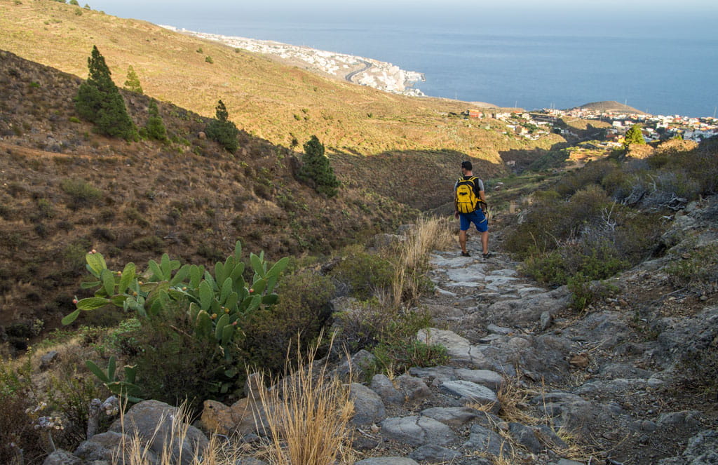 Person walking on path to the sea in the mountainous landscape of Tenerife.