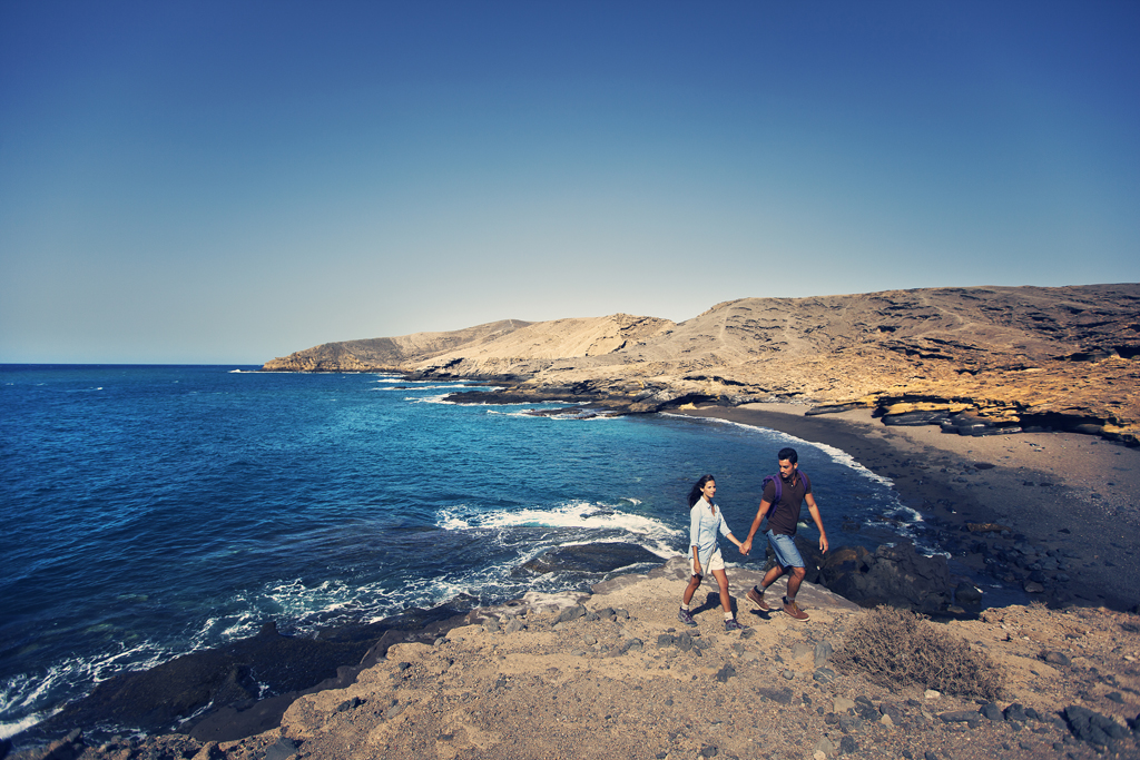 Couple walking by the sea in a coastal landscape of Tenerife.