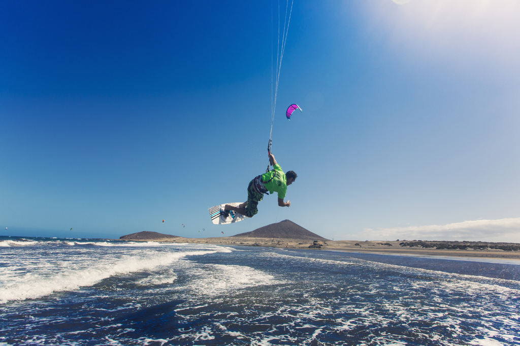 Person kitesurfing on El Médano beach, Tenerife, with clear skies.