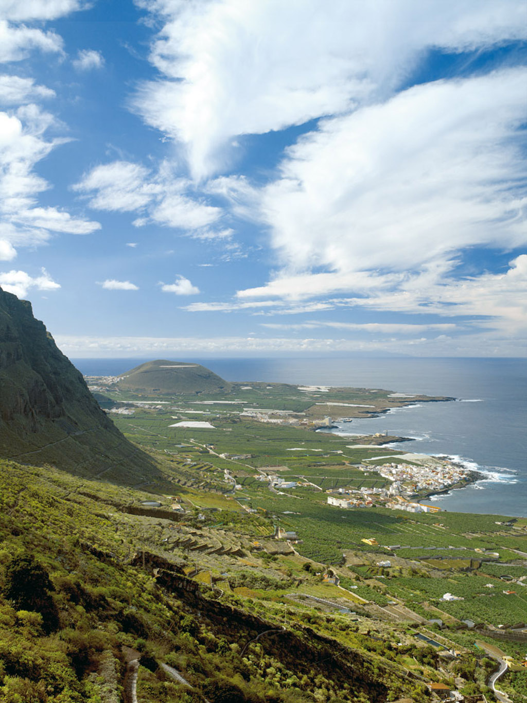 Panoramic view of Garachico, Tenerife, with mountains and the Atlantic Ocean in the background.