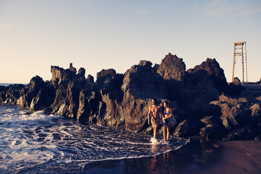 People walking along the beach next to rocks in Bajamar, Tenerife.