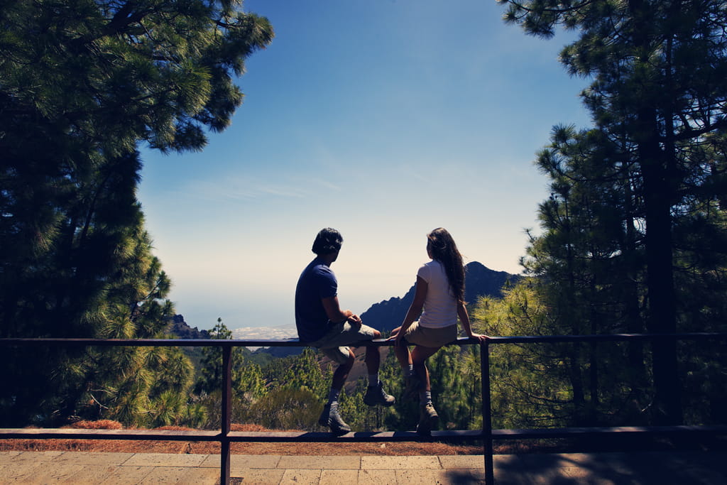 Two people sitting on a viewpoint overlooking the sea in Tenerife.