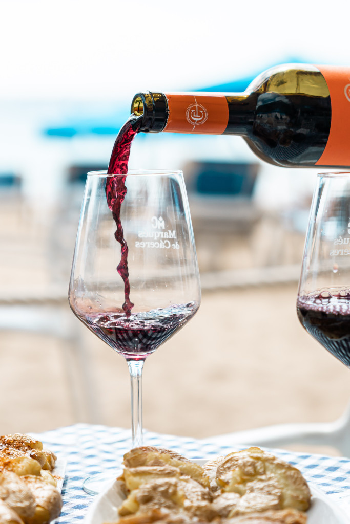 Red wine poured into a glass with cakes on a beach table in Tenerife.