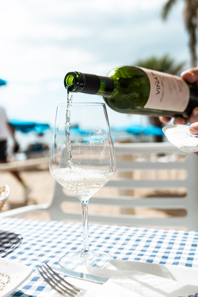 White wine being served in a glass on a table with a checkered tablecloth in Tenerife.
