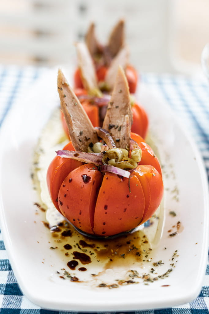 Tomatoes stuffed with tuna and onion on a white plate on a table in Tenerife.