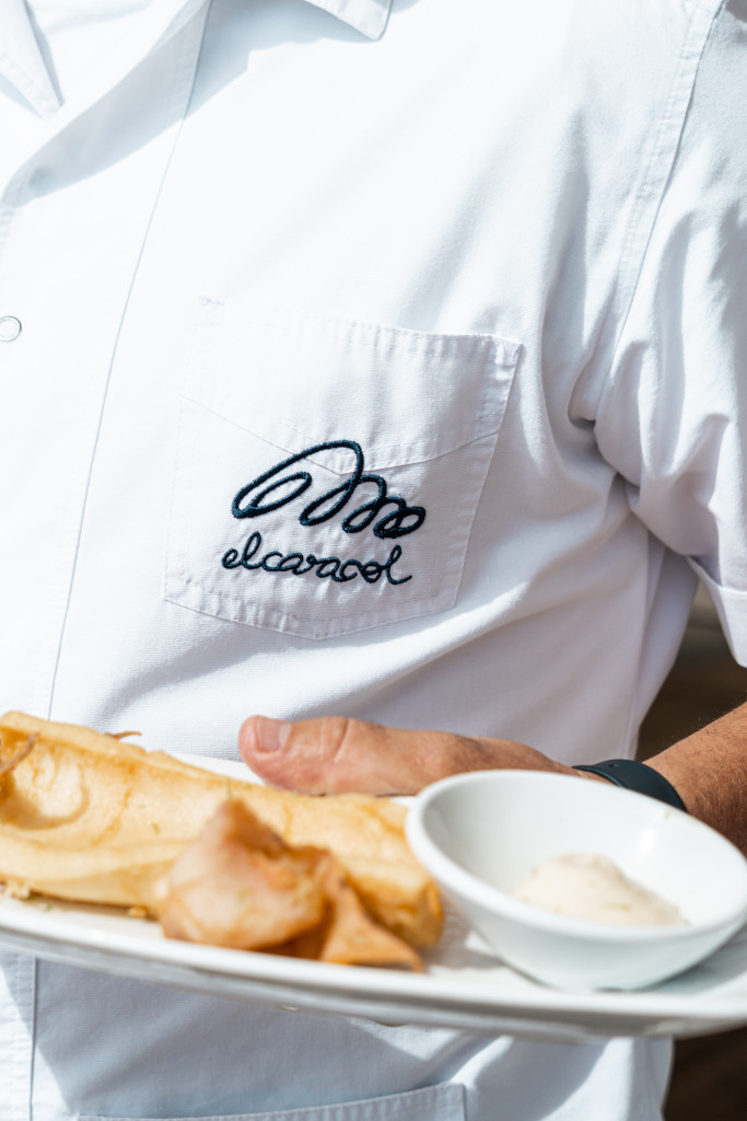 Waiter in white snail shirt carrying plate of food.