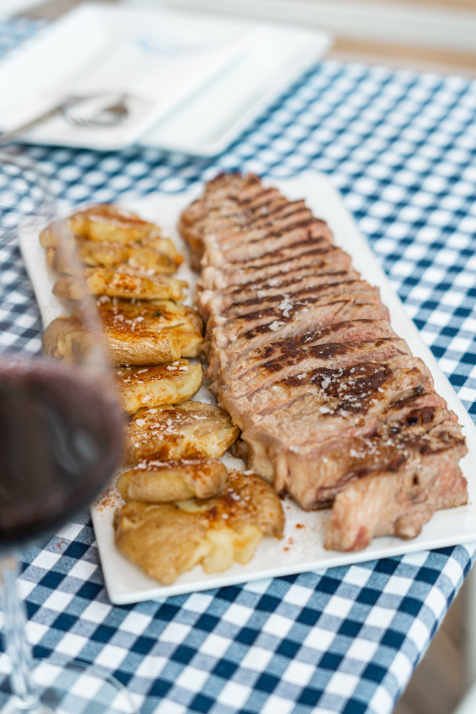 Grilled meat with potatoes on a plate on a checkered tablecloth in Tenerife.