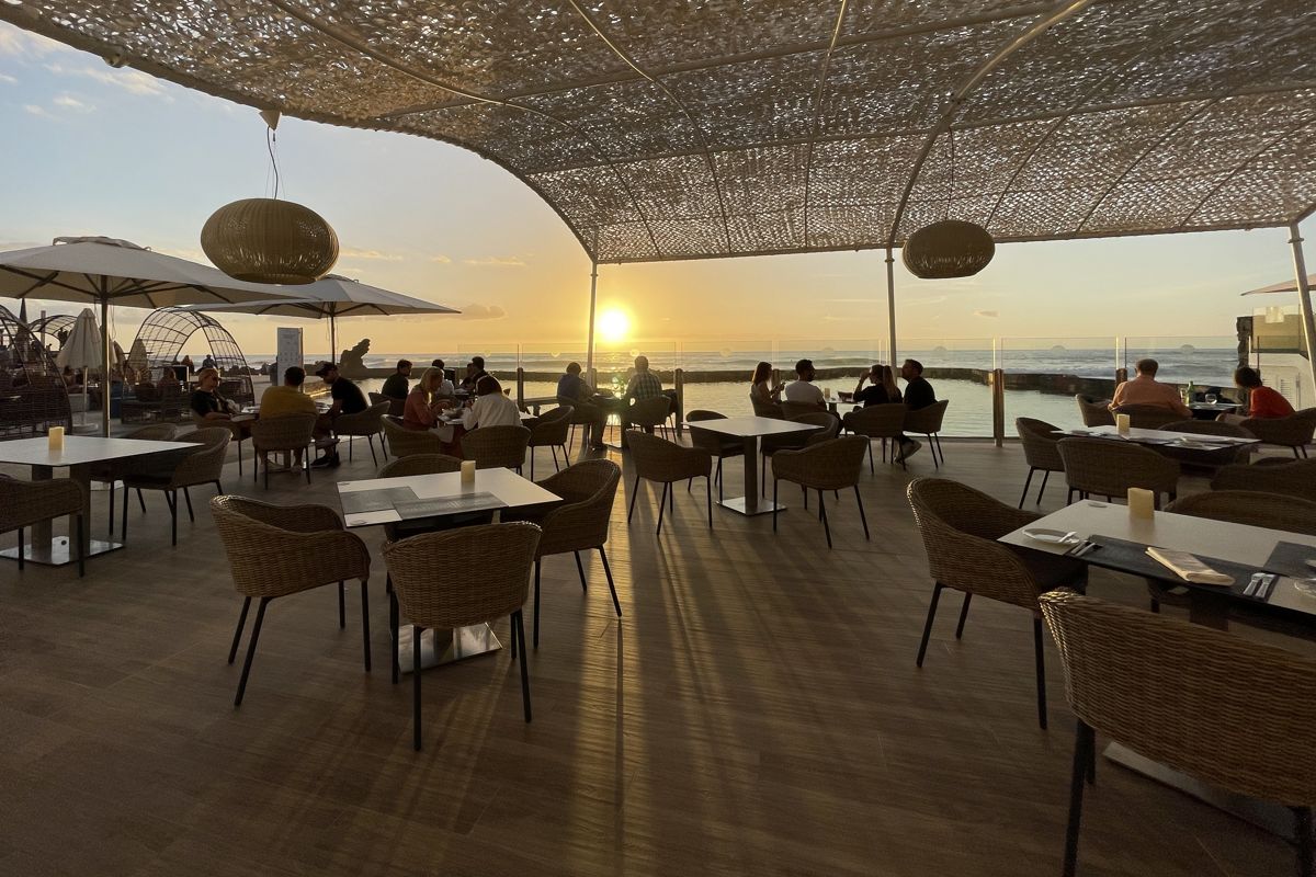 People dining at sunset on a terrace overlooking the sea in Tenerife.