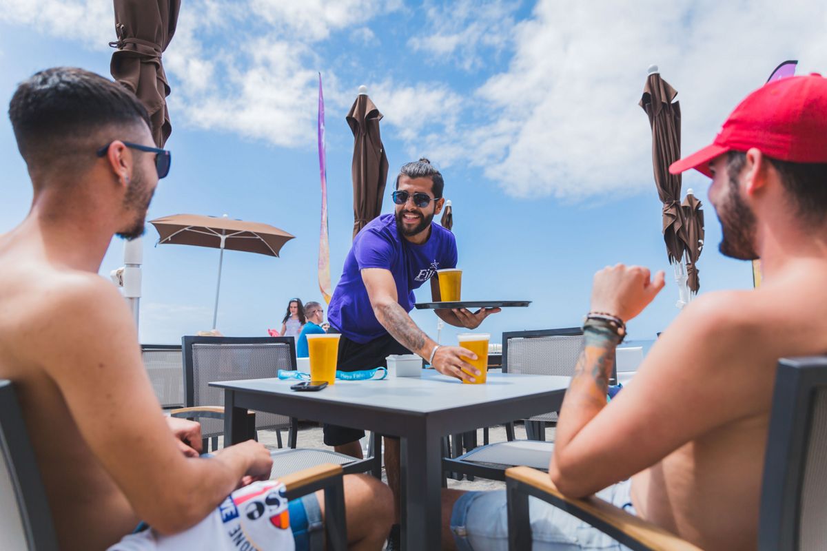 Waiter serving beers to two men on a terrace in Tenerife.