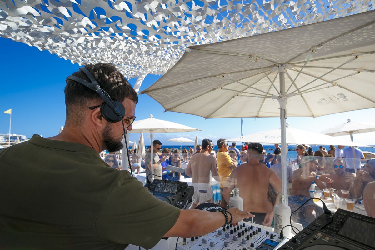 DJ at an outdoor event on the beach in Tenerife with an audience enjoying themselves.