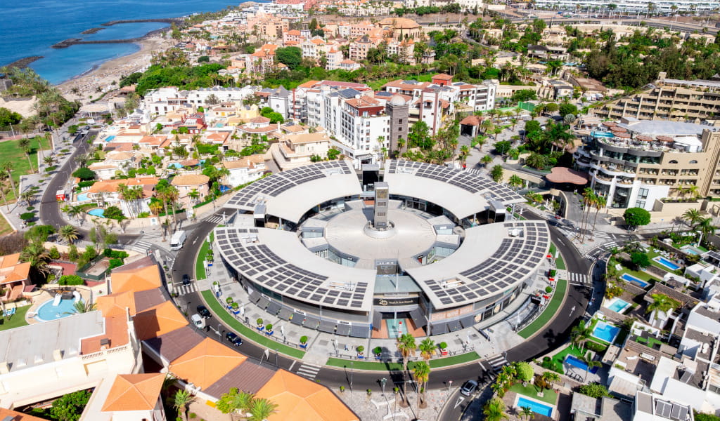 Aerial view of the Plaza del Duque shopping centre in Tenerife, surrounded by buildings and the sea.