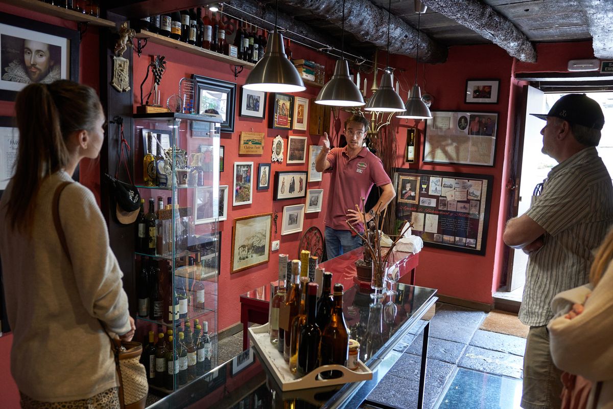 Man explaining about wines to tourists, surrounded by bottles and decorations in Tenerife.