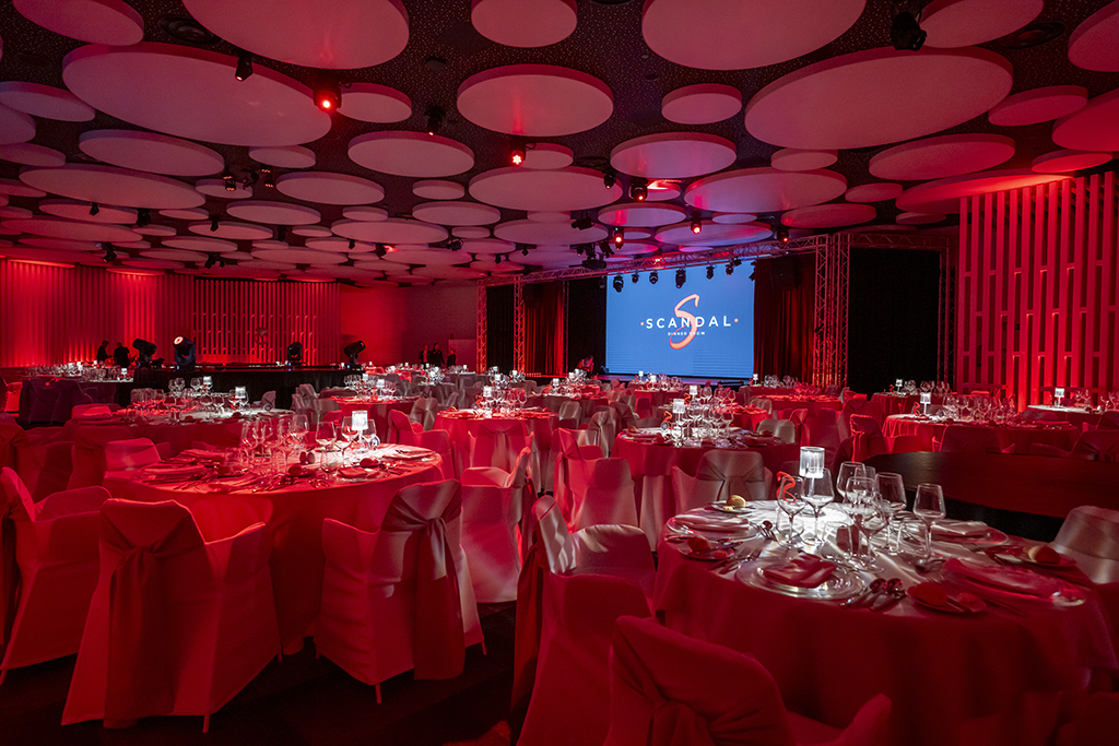 Event room with decorated tables and screen with SCANDAL Show Tenerife logo.