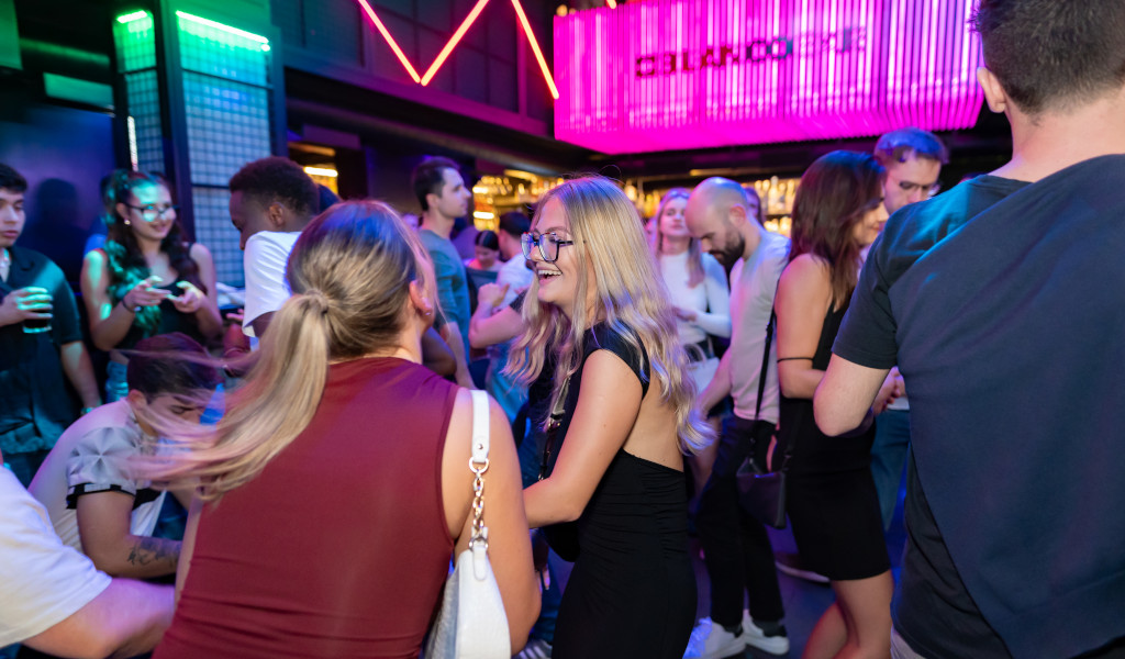 People socializing and dancing in a lit nightclub in Tenerife.