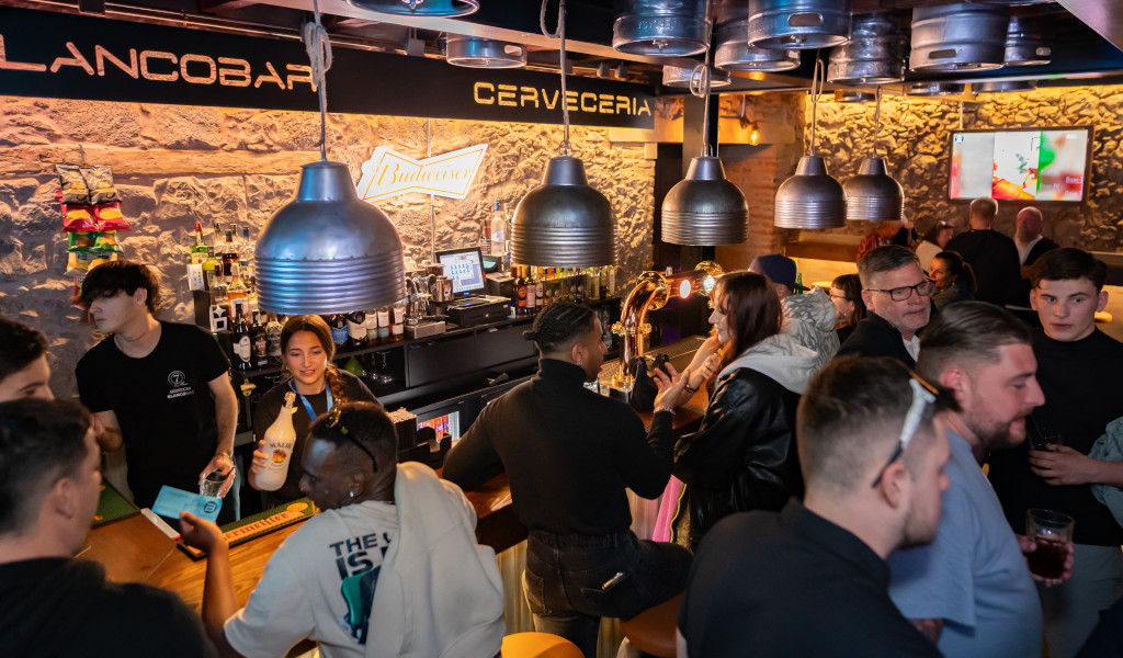 People chatting at the bar of a brewery in Tenerife, with a Budweiser sign.