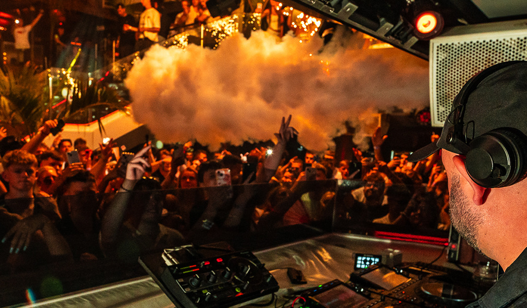 DJ playing live in front of a lively crowd in a club in Tenerife.